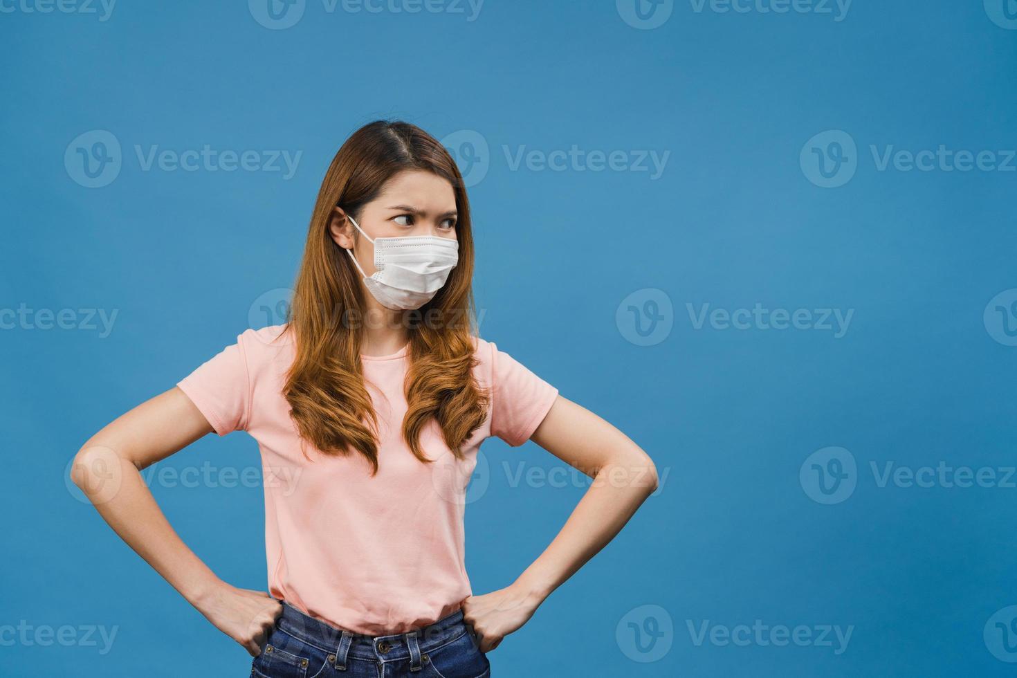 junge asiatische Mädchen tragen medizinische Gesichtsmaske mit negativem Ausdruck, aufgeregtem Schrei, weinen emotional wütend und betrachten die Kamera einzeln auf blauem Hintergrund. soziale Distanzierung, Quarantäne wegen Corona-Virus. foto