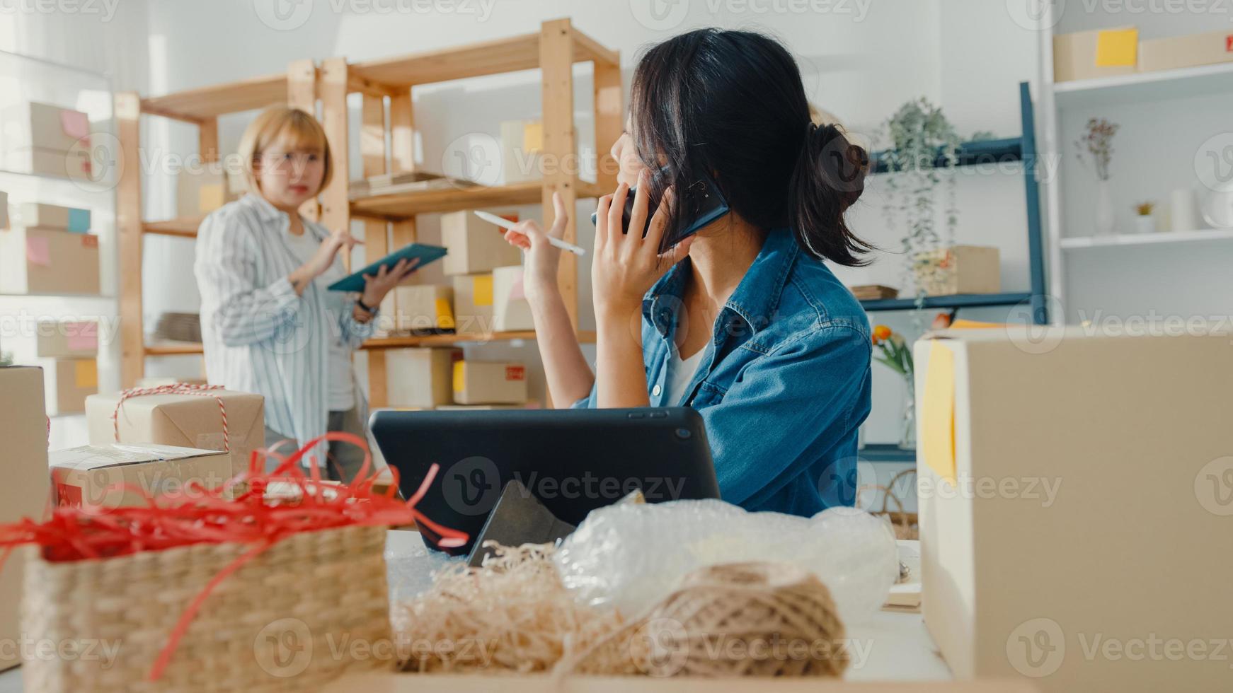 Junge Geschäftsfrauen in Asien, die einen Handyanruf verwenden, erhalten eine Bestellung und überprüfen das Produkt auf Lager im Home Office. Kleinunternehmer, Online-Marktlieferung, Lifestyle-Freelance-Konzept. foto