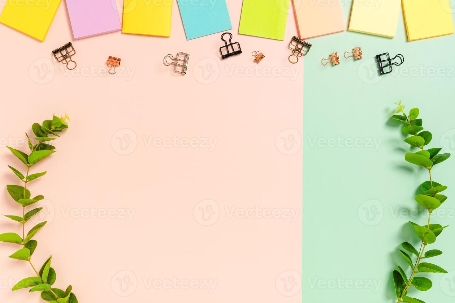 minimaler arbeitsplatz - kreatives flaches foto des arbeitsplatzes. Schreibtisch von oben mit Haftnotiz auf pastellgrünem rosafarbenem Hintergrund. Draufsicht mit Kopienraum, Flachfotografie.