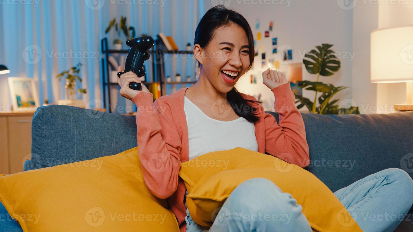 junge asiatische Dame mit Wireless-Controller spielen Videospiel mit lustigen glücklichen Moment auf dem Sofa im Wohnzimmer zu Hause Nacht. Bleiben Sie zu Hause, Selbstquarantäne-Aktivität für Covid- oder Coronavirus-Quarantäne. foto