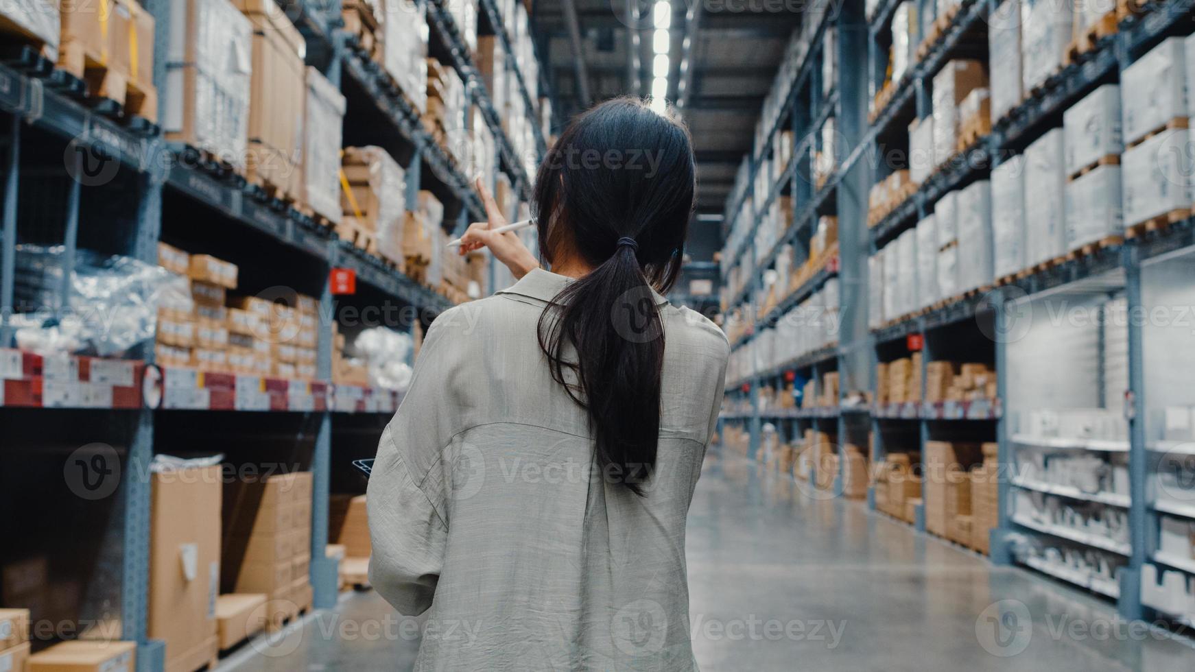 Junge asiatische Geschäftsfrau-Manager tragen Gesichtsmaske auf der Suche nach Waren mit digitaler Tablette, die die Lagerbestände im Einzelhandels-Einkaufszentrum überprüft. Distribution, Logistik, versandfertige Pakete. foto