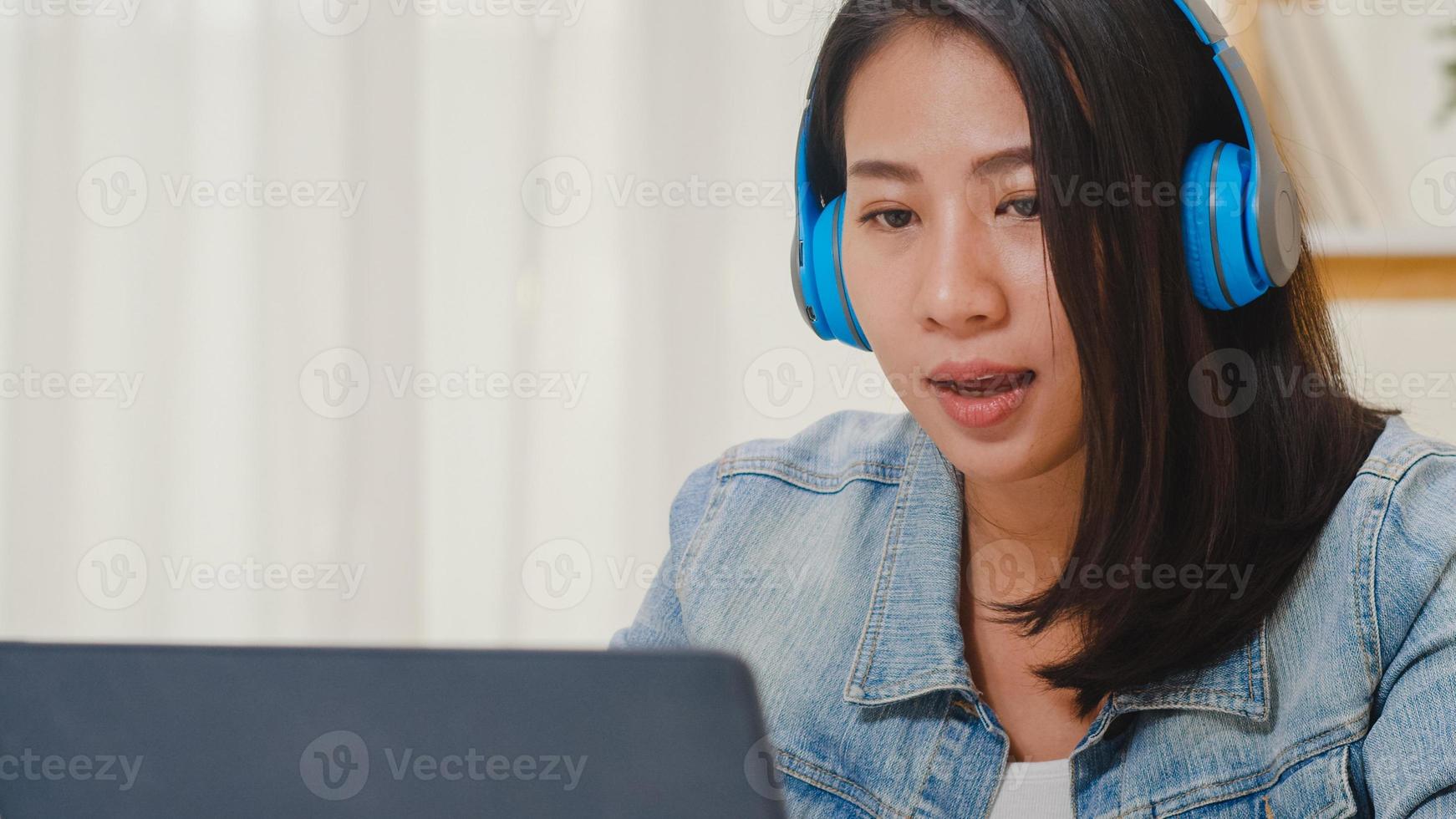 Freiberufliche Geschäftsfrauen Freizeitkleidung mit Laptop-Videokonferenz mit Kunden am Arbeitsplatz im Wohnzimmer zu Hause. glückliche junge asiatische mädchen entspannen sich auf dem schreibtisch sitzend, arbeiten im internet. foto