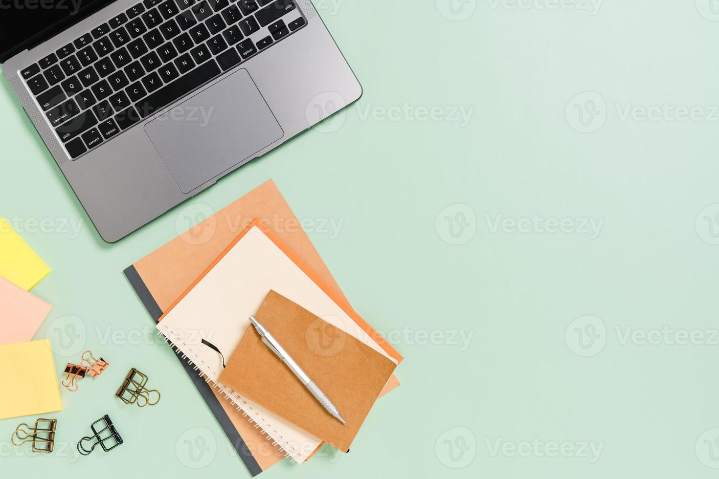 kreatives flaches Laienfoto des Arbeitsplatzschreibtisches. Schreibtisch von oben mit Laptop, Kaffeetasse und offenem schwarzen Notizbuch auf pastellgrünem Hintergrund. Draufsichtmodell mit Kopienraumfotografie. foto