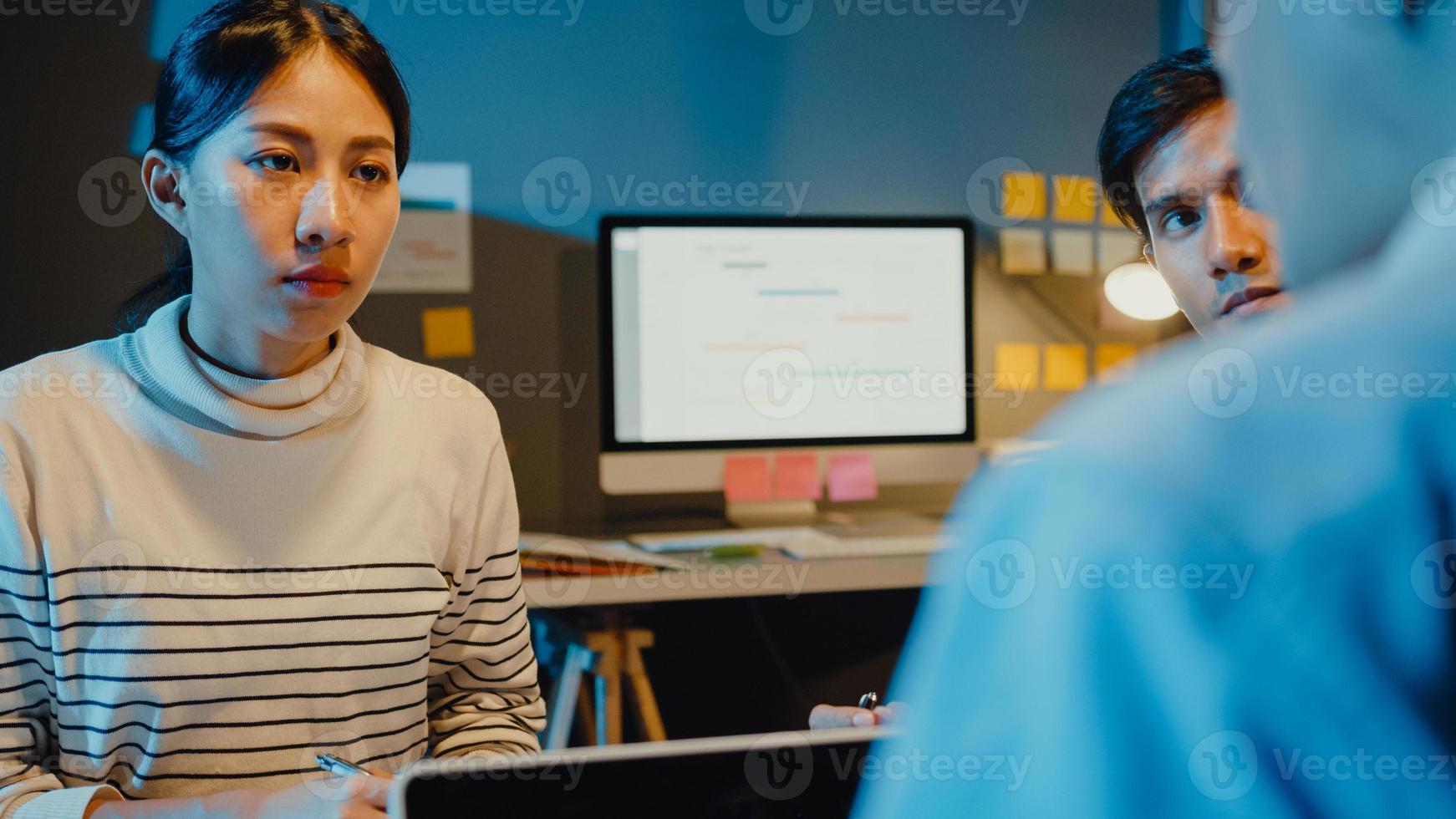 glückliche junge asiatische geschäftsleute und geschäftsfrauen, die sich treffen, um einige neue projektideen mit seinem partner zu brainstormen, der zusammen die erfolgsstrategie plant, genießen teamarbeit in einem kleinen modernen nachtbüro. foto