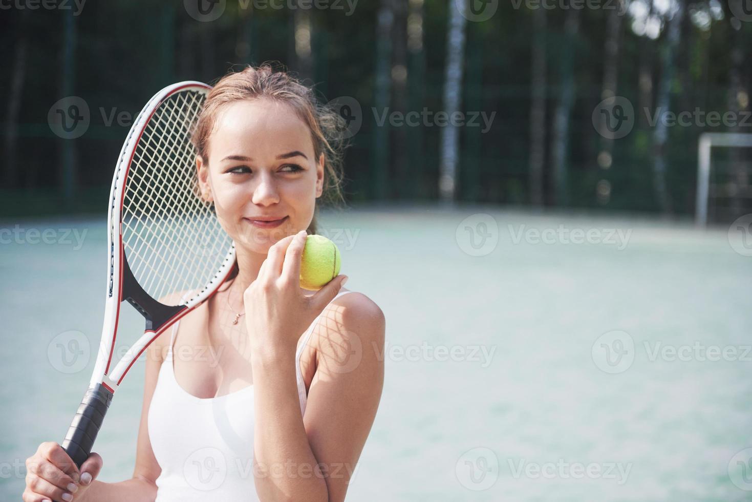 süßes Mädchen, das Tennis spielt und für die Kamera posiert. foto
