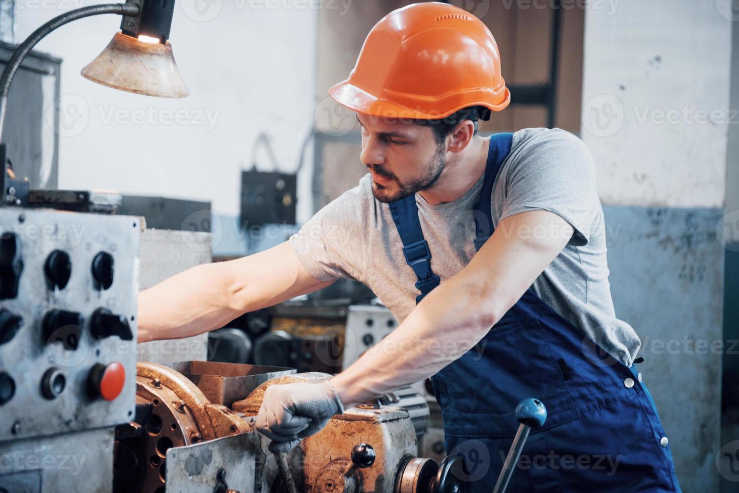 erfahrener Bediener mit Schutzhelm. Konzept der Metallverarbeitungsindustrie Berufsingenieur Metallarbeiter, der CNC-Fräsmaschinenzentrum in der Fertigungswerkstatt betreibt foto