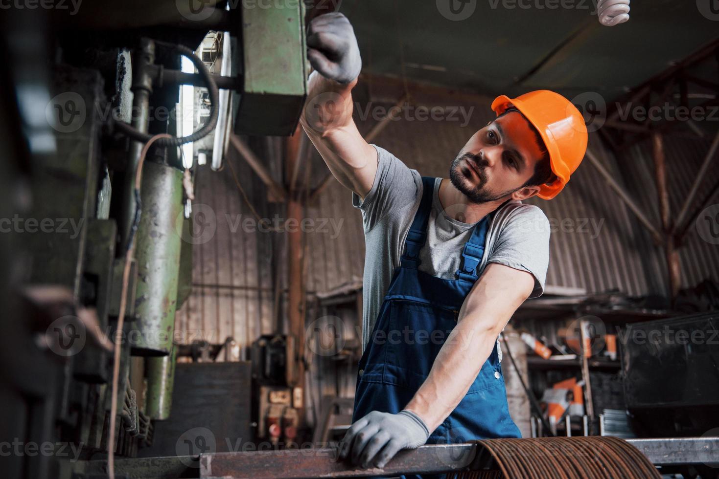 Porträt eines jungen Arbeiters mit Schutzhelm in einem großen Metallwerk. der ingenieur bedient die maschinen und fertigt teile für gasanlagen foto