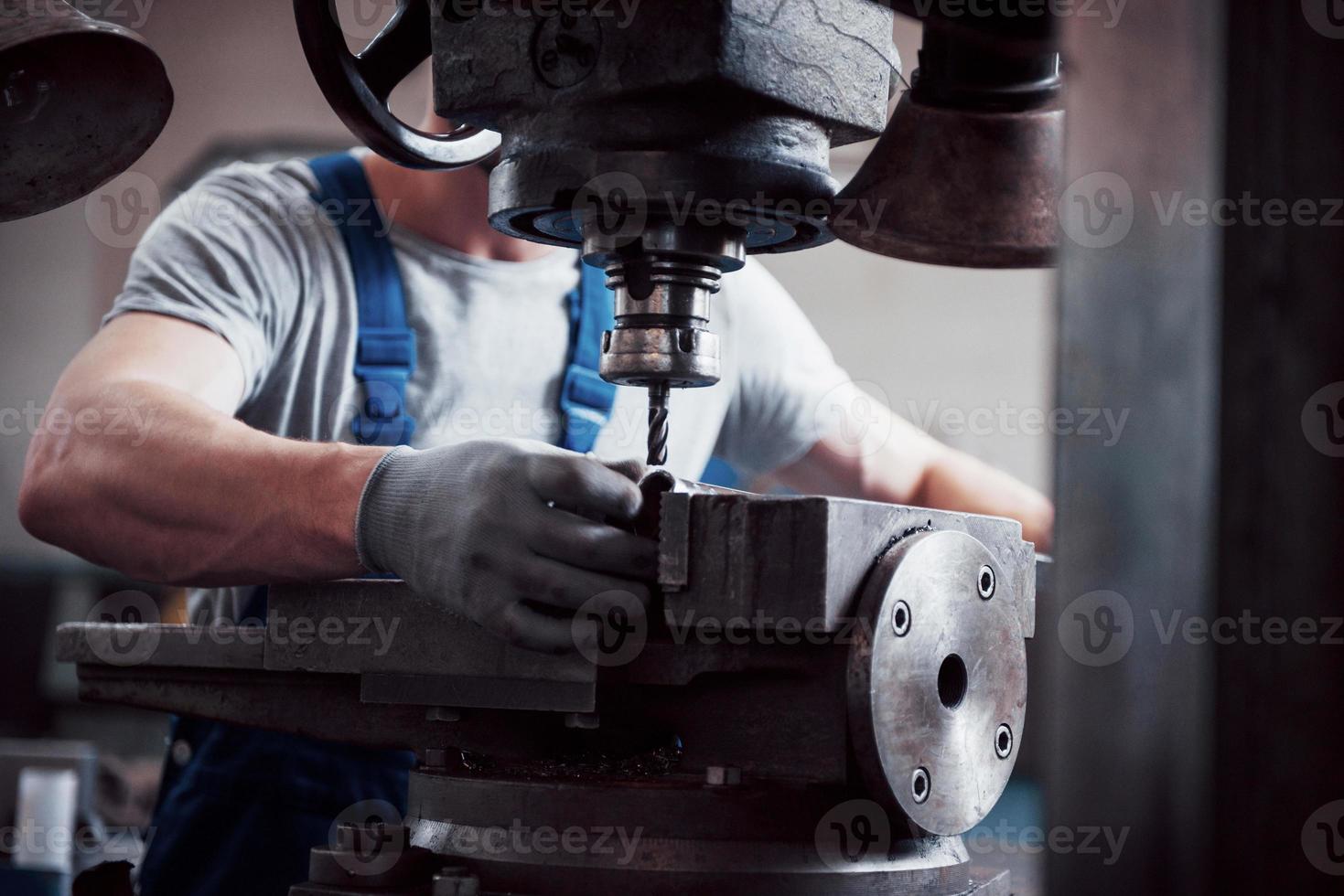 Porträt eines jungen Arbeiters mit Schutzhelm in einem großen Metallwerk. der ingenieur bedient die maschinen und fertigt teile für gasanlagen foto