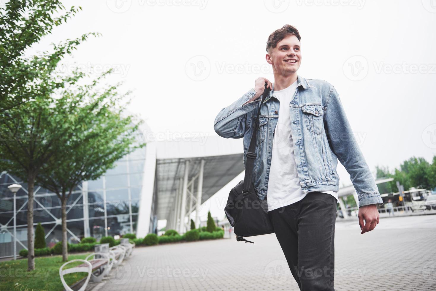 ein junger schöner mann am flughafen wartet auf den flug. foto