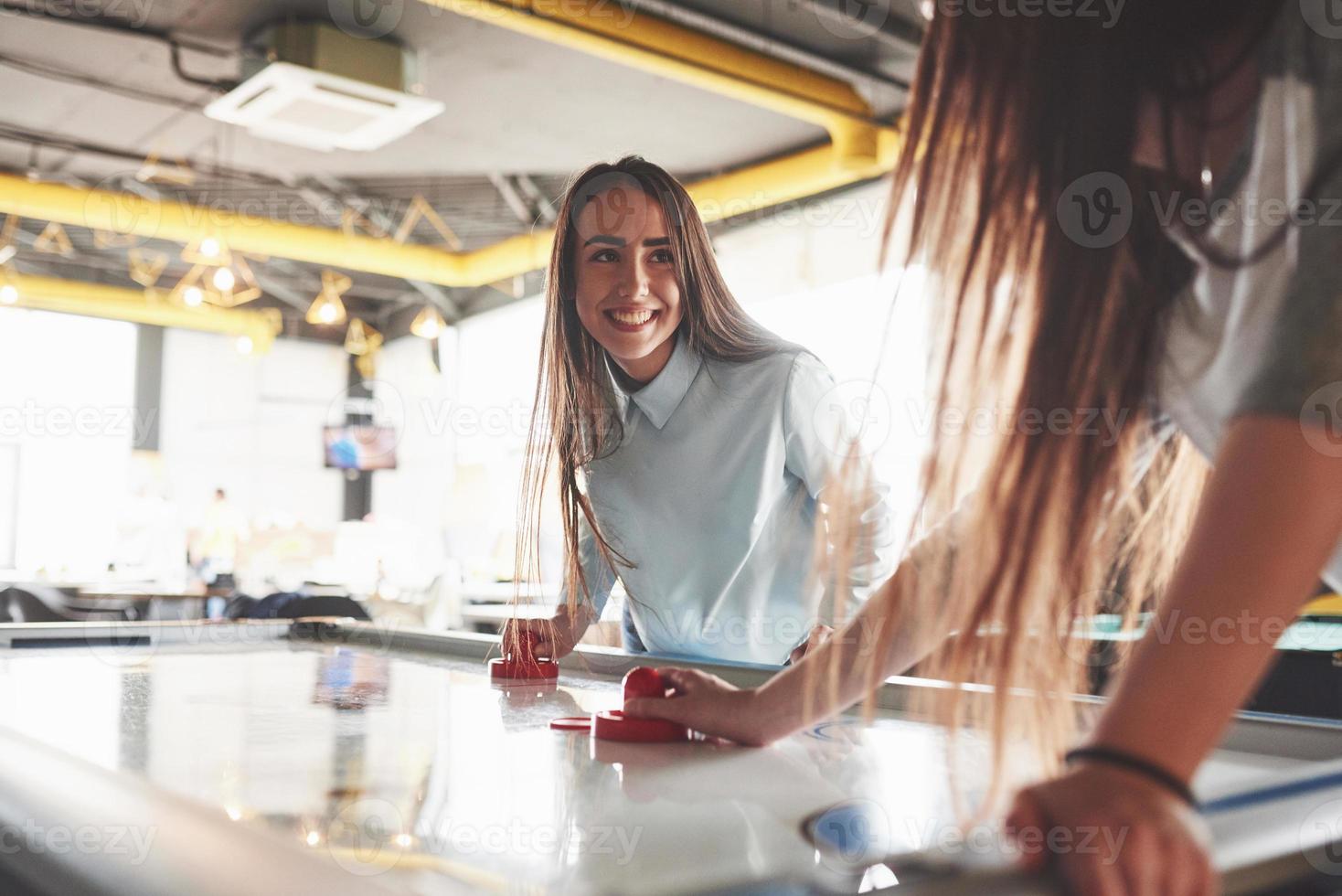 zwei schöne Zwillingsmädchen spielen Airhockey im Spielzimmer und haben Spaß foto