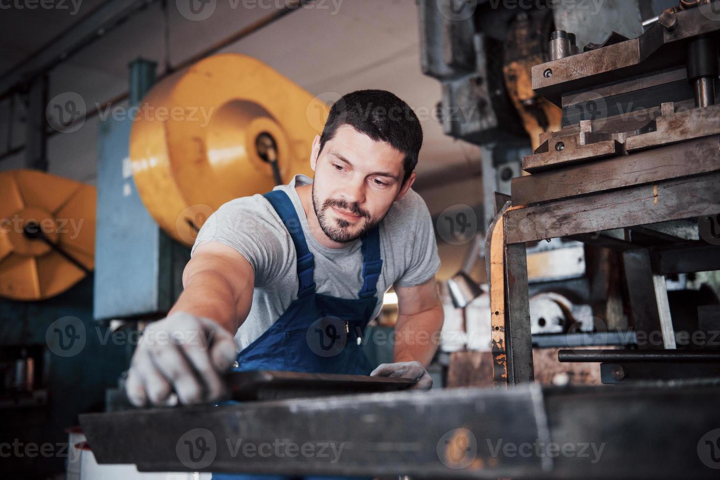 erfahrener Bediener mit Schutzhelm. Konzept der Metallverarbeitungsindustrie Berufsingenieur Metallarbeiter, der CNC-Fräsmaschinenzentrum in der Fertigungswerkstatt betreibt foto