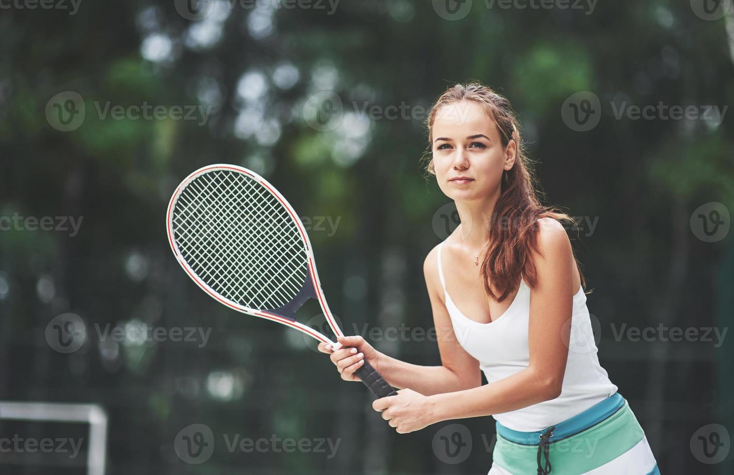 eine schöne frau, die einen tennisball in sportkleidung trägt. foto