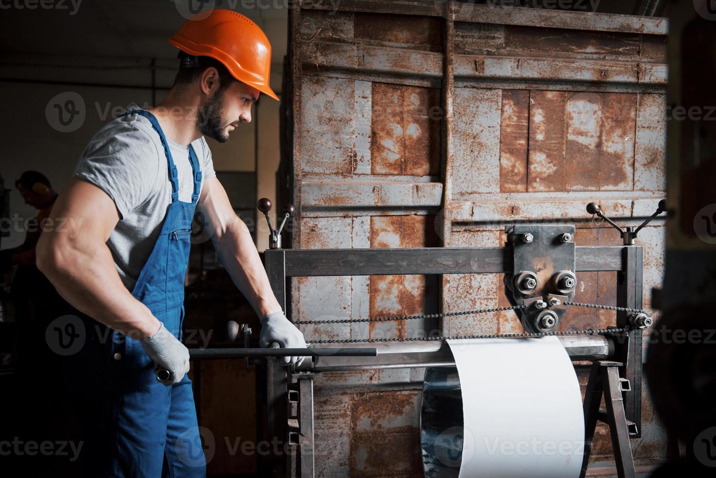 Porträt eines jungen Arbeiters mit Schutzhelm in einem großen Metallwerk. der ingenieur bedient die maschinen und fertigt teile für gasanlagen foto