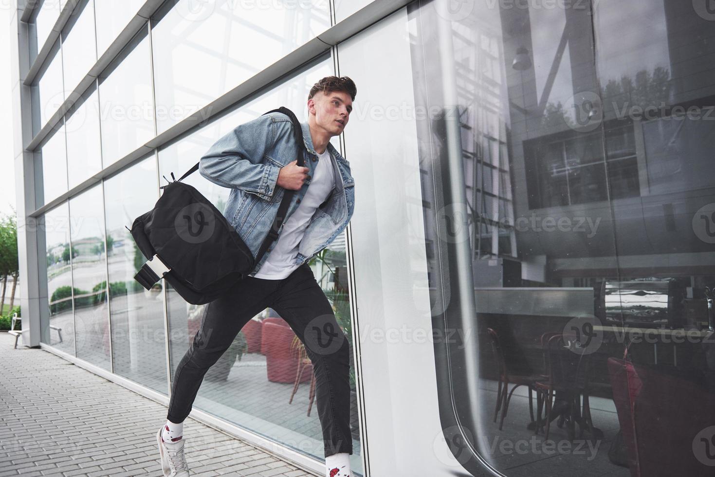 ein junger schöner mann am flughafen wartet auf den flug. foto