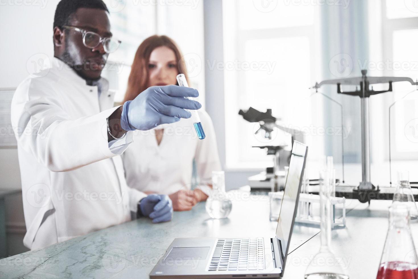 Laborlabore führen Experimente in einem chemischen Labor in transparenten Kolben durch. Ausgabeformeln foto