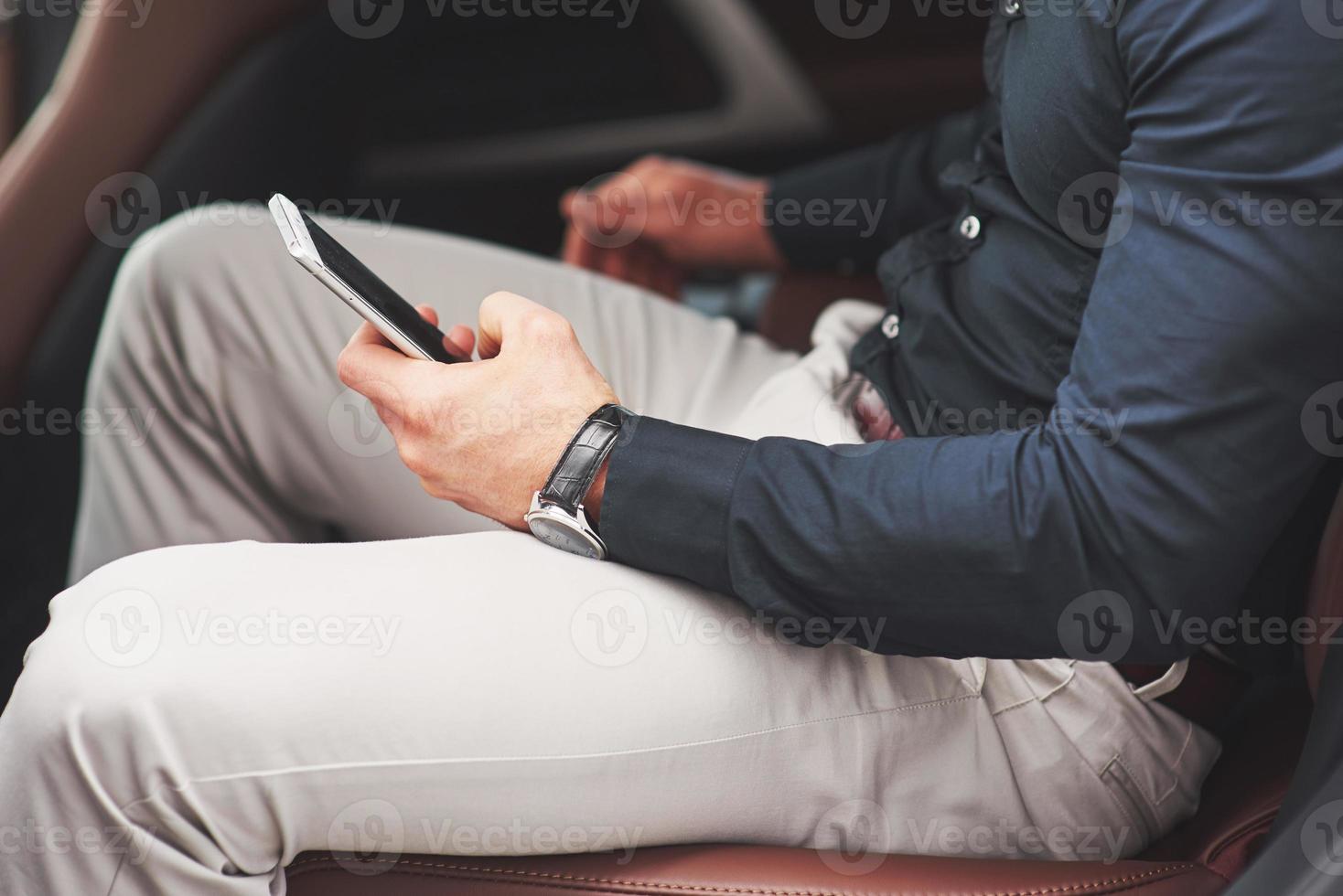 ein Geschäftsmann, der eine Nachricht an ein Smartphone sendet und auf den Rücksitz des Autos geht. foto