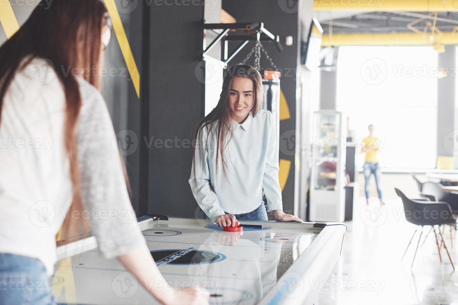 zwei schöne Zwillingsmädchen spielen Airhockey im Spielzimmer und haben Spaß foto