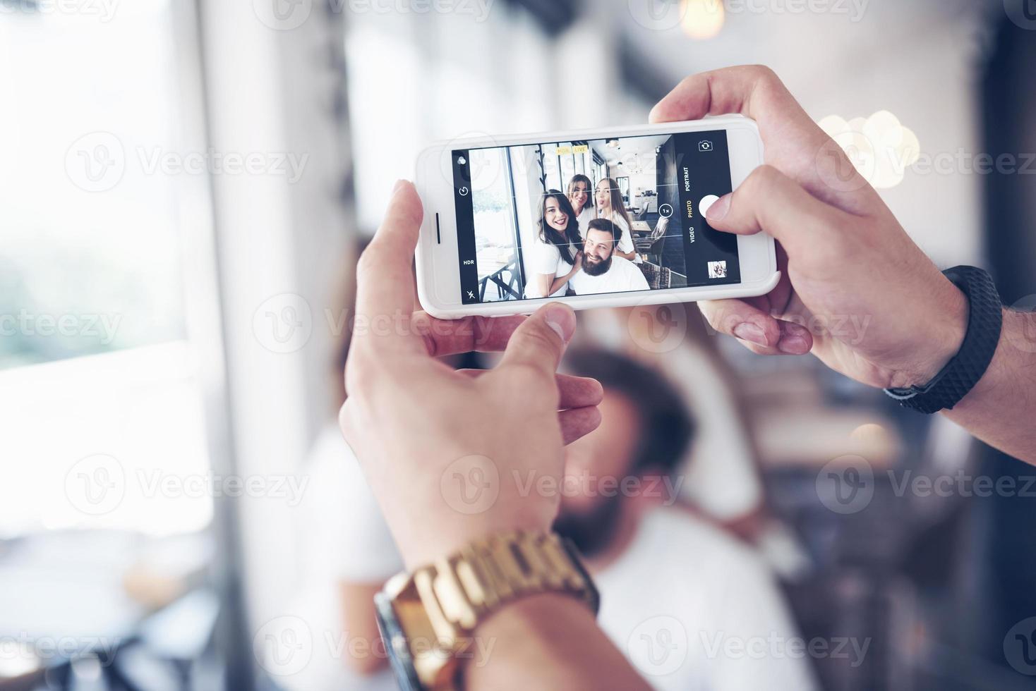 Unschärfeporträt von glückseligen jungen besten Freunden mit den Händen, die das Telefon im Vordergrund halten foto