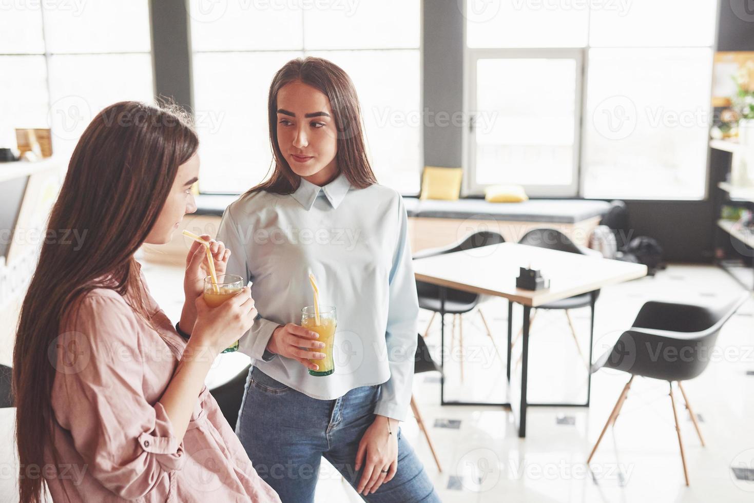 zwei schöne Zwillingsmädchen verbringen Zeit damit, Saft zu trinken. Schwestern, die sich in einem Café entspannen und zusammen Spaß haben foto