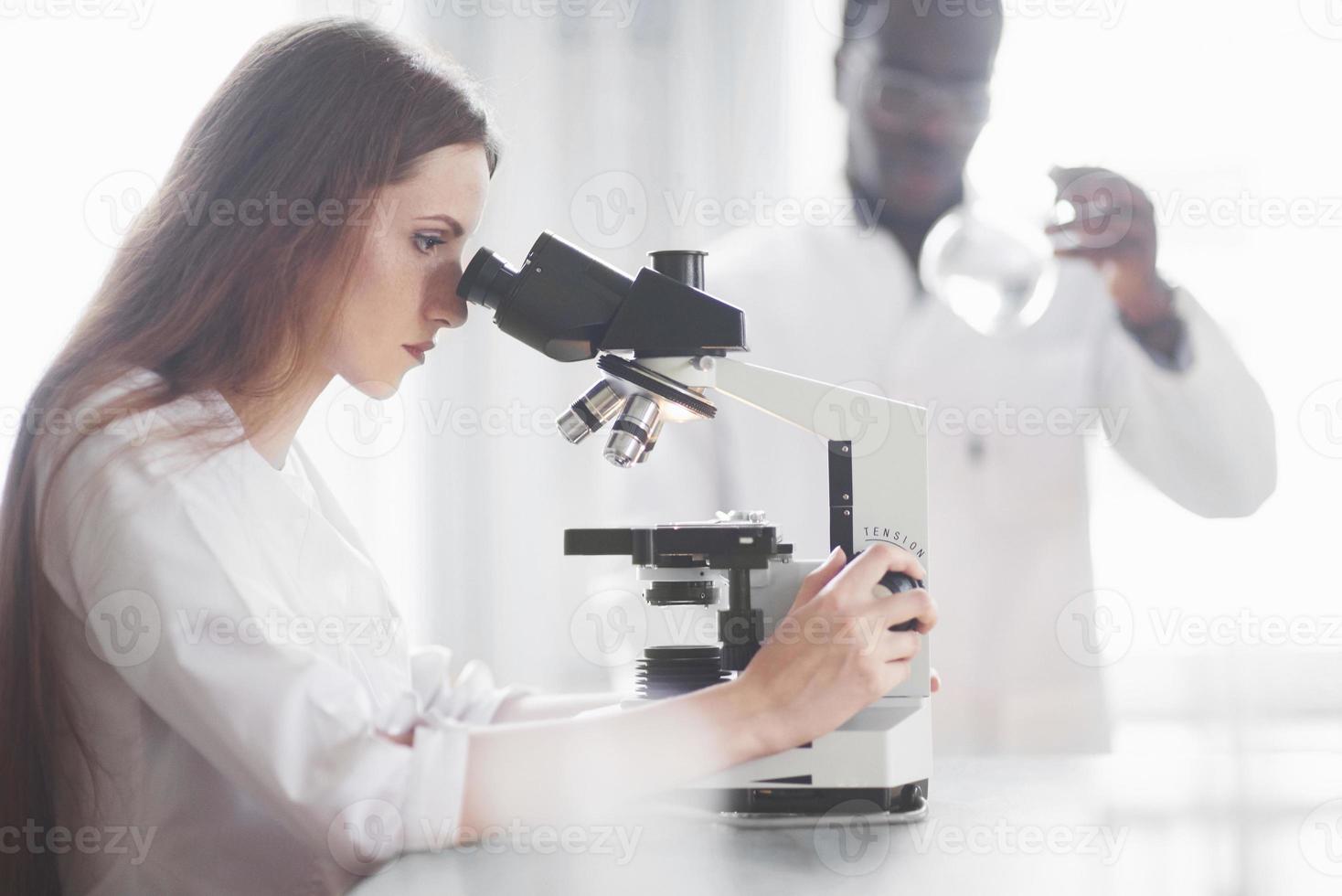 Laborassistent mit Mikroskop Laborglasbirne mit Chemikalien. foto