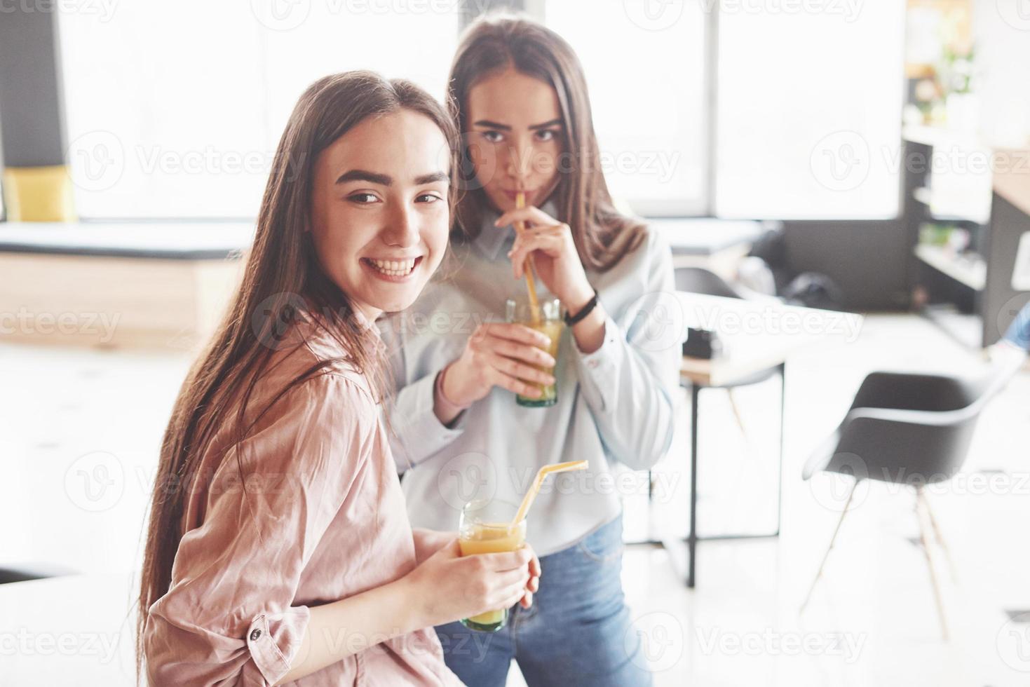 zwei schöne Zwillingsmädchen verbringen Zeit damit, Saft zu trinken. Schwestern, die sich in einem Café entspannen und zusammen Spaß haben foto