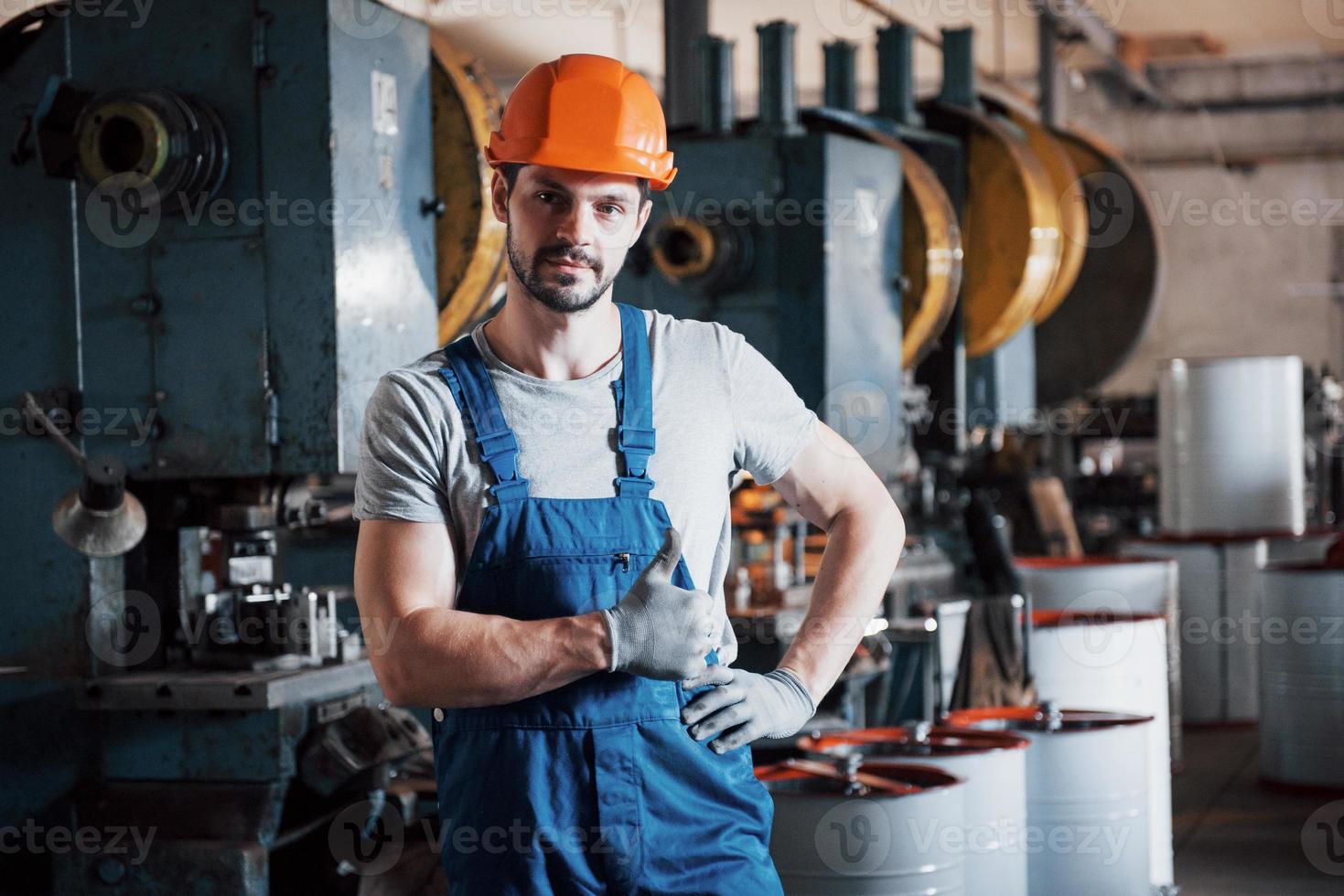 Porträt eines jungen Arbeiters mit Schutzhelm in einem großen Metallwerk. der ingenieur bedient die maschinen und fertigt teile für gasanlagen foto