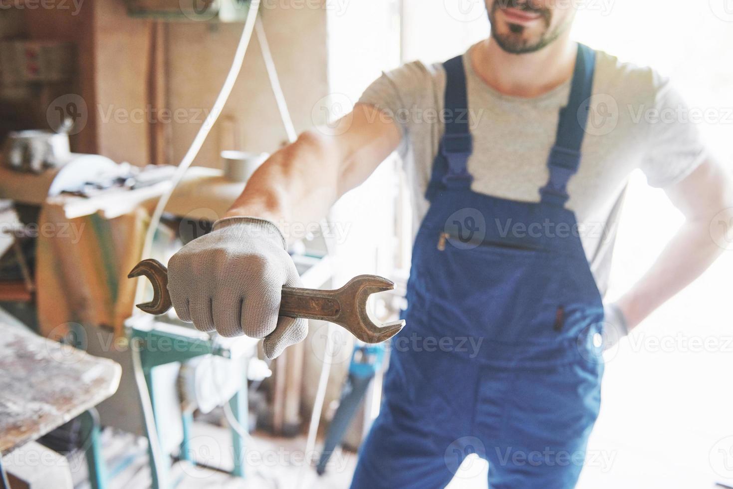 Meister in Arbeitsform und Handschuhe mit einem Schlüssel in der Hand. foto