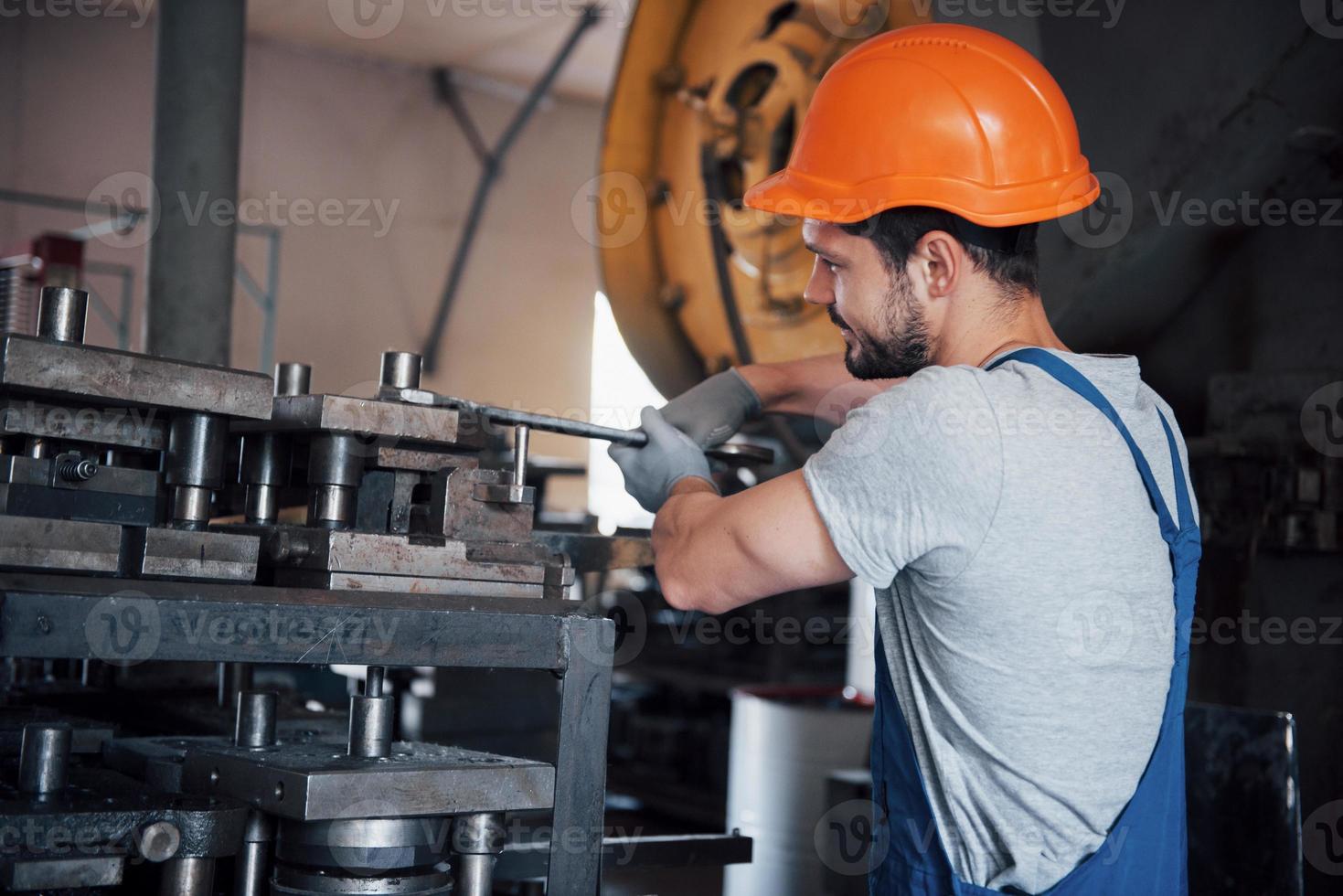 Porträt eines jungen Arbeiters mit Schutzhelm in einem großen Metallwerk. der ingenieur bedient die maschinen und fertigt teile für gasanlagen foto