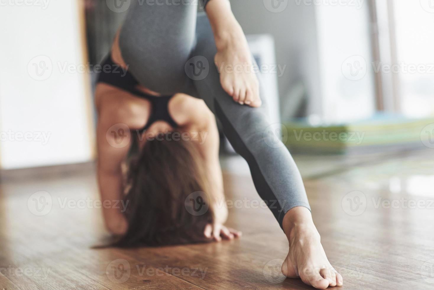 eine schöne Yoga-Frau, die in einem geräumigen, hellen Fitnessstudio praktiziert foto