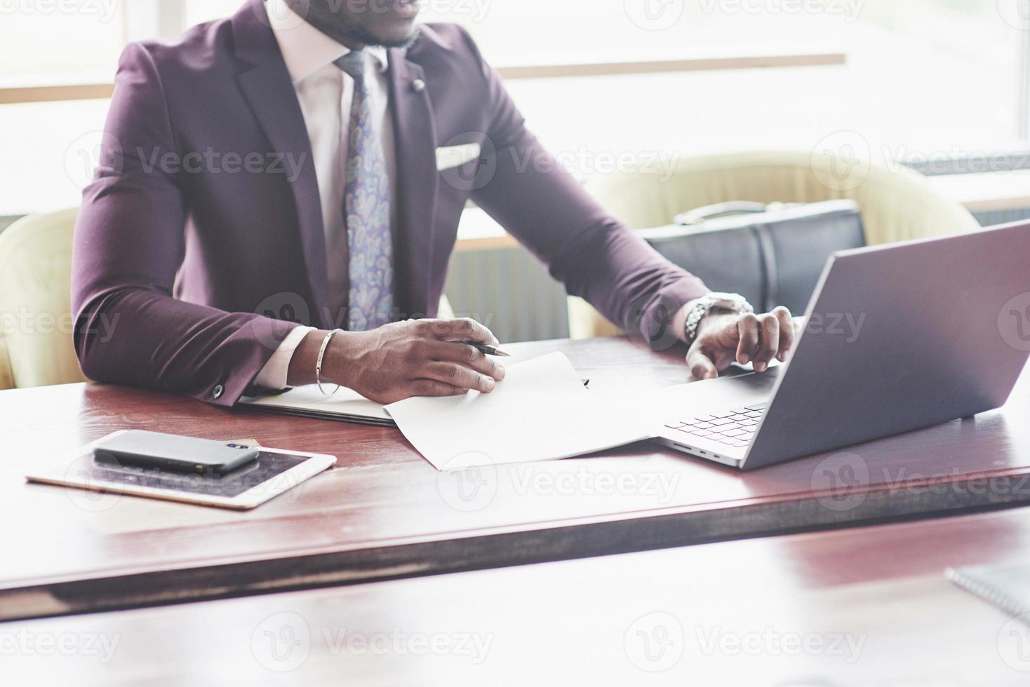 Eine schöne, stilvolle afroamerikanische Geschäftsfrau, die einen Anzug trägt, benutzt ihren Laptop während der Arbeit. foto