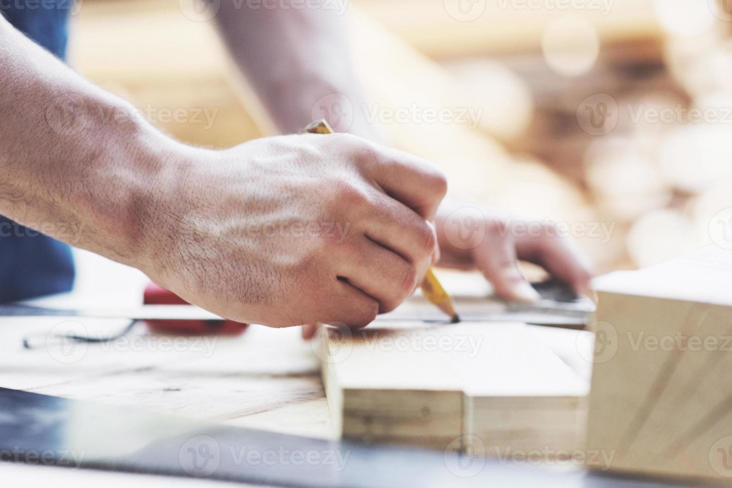 ein Tischler in Arbeitskleidung und ein Kleinunternehmer nehmen ein Holzbrett mit Lineal und Bleistift. foto