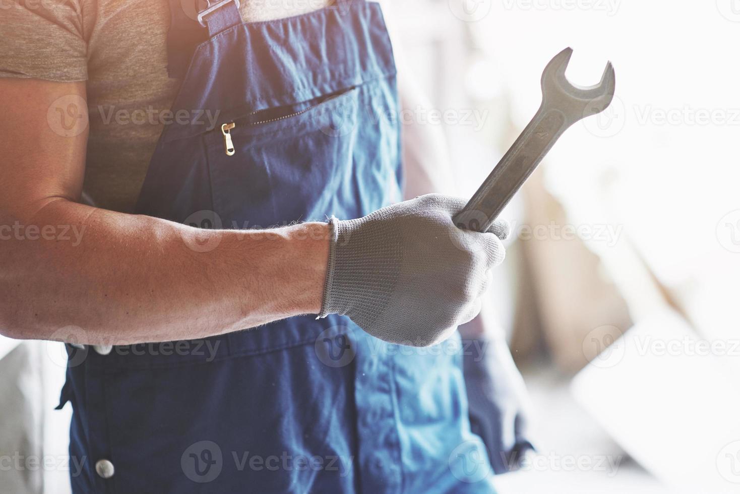 Handschuhe mit einem Metallschlüssel vor dem Hintergrund der Kostümfabrik eines Arbeiters abgeben. foto