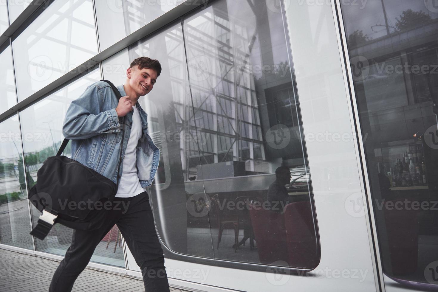 ein junger schöner mann am flughafen wartet auf den flug. foto