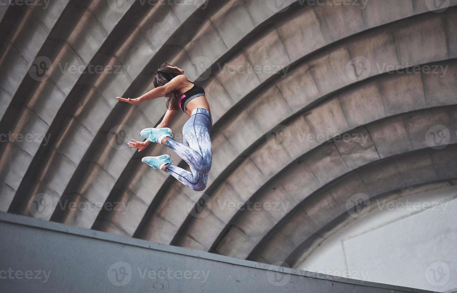 Frau macht Parkour in der Stadt an einem sonnigen Tag foto