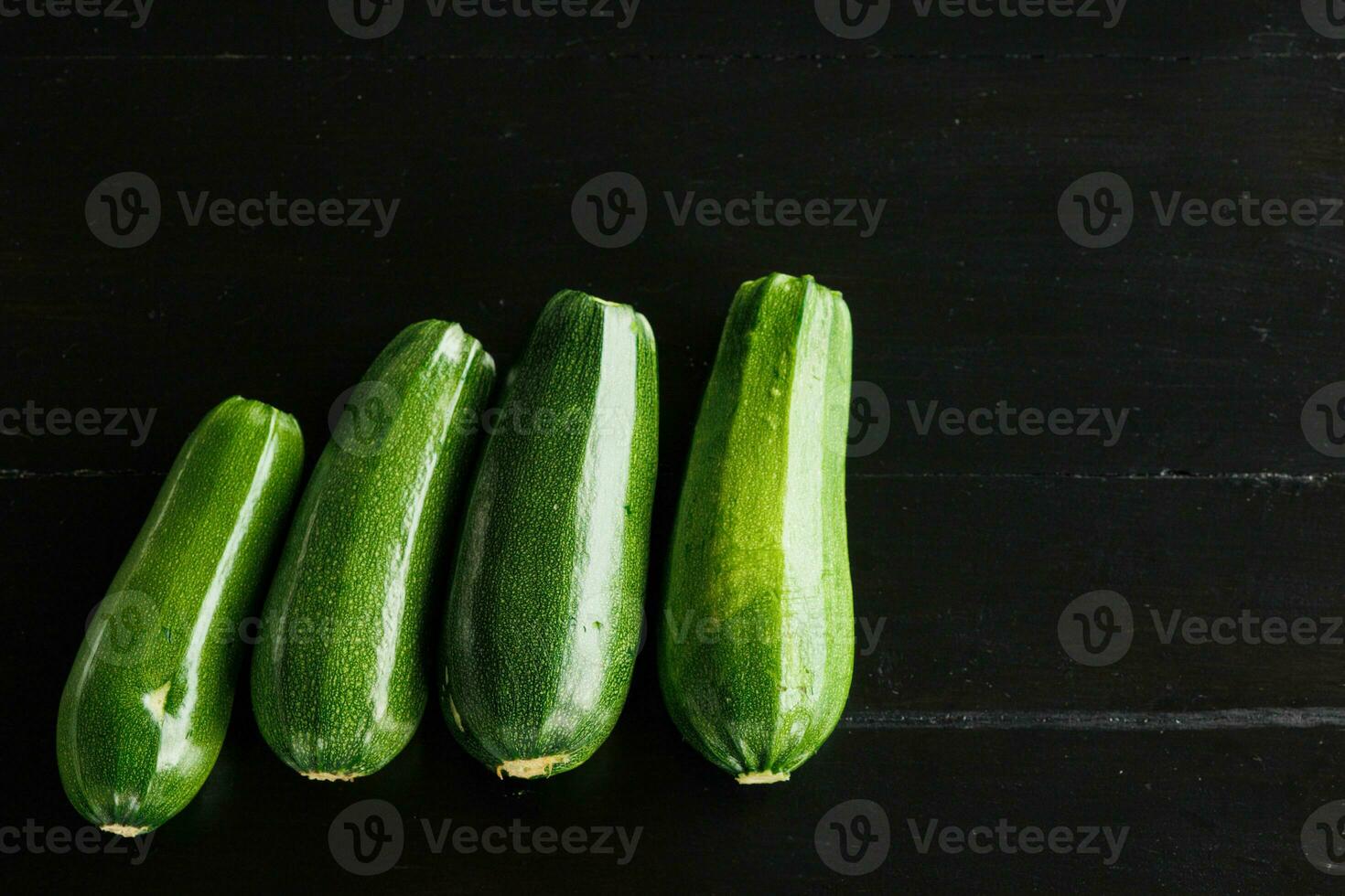 vier Grün frisch Zucchini auf ein schwarz Hintergrund. Konzept von gesund Essen foto