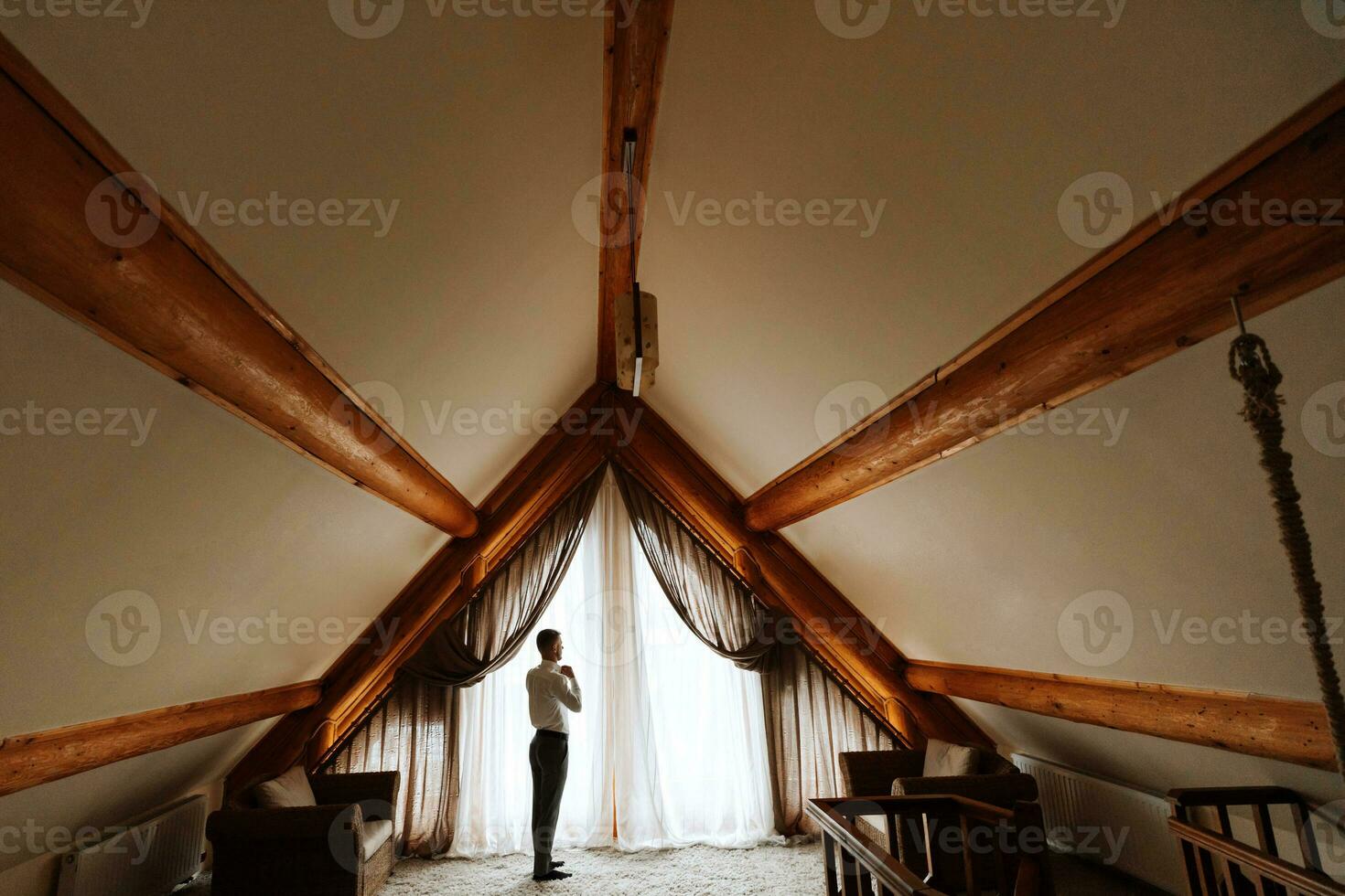 ein Mann ist Stehen durch das Fenster im ein Hotel Zimmer. breit planen Foto. das Bräutigam Kleider und bereitet vor zum das Hochzeit. ein wunderbar Innere zum Entspannung foto