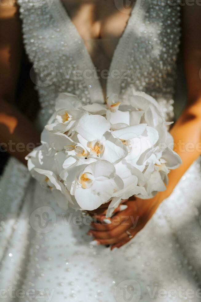 Hochzeit im europäisch Stil. Porträt von das Braut im ein klassisch Stil, Weiß Kleid, Strauß von Orchidee Blumen. foto