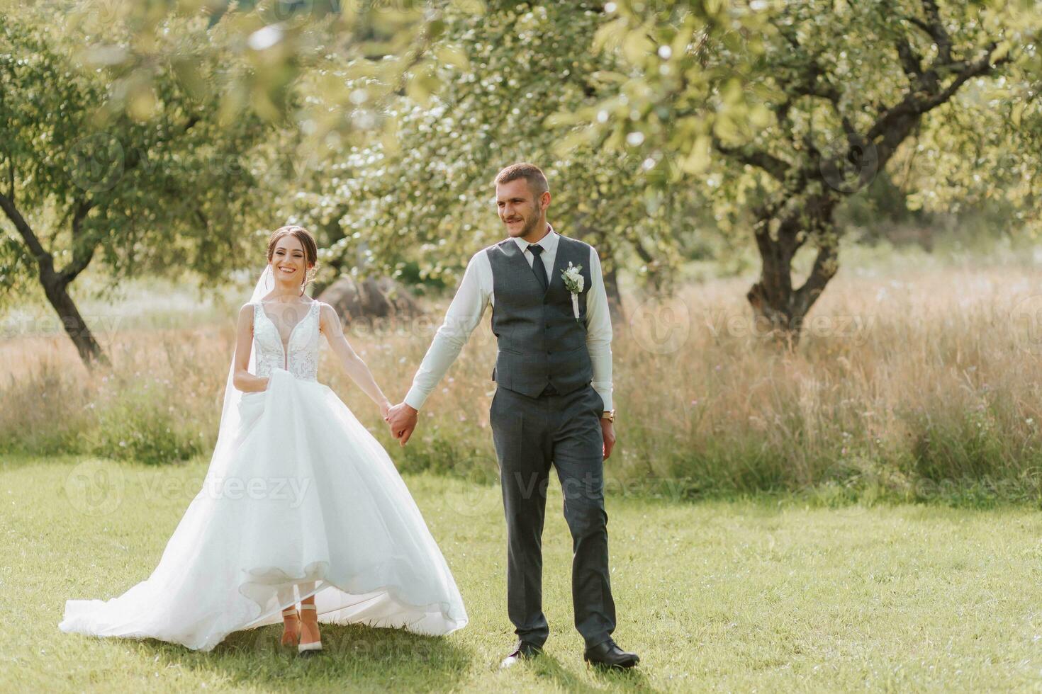 ein schön Hochzeit, ein schön Paar im Liebe, Gehen auf das Hintergrund von ein Grün Garten mit hoch Grün Bäume. hoch Qualität Foto