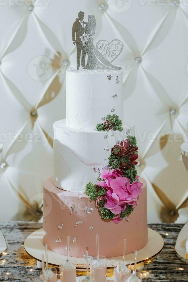 ein köstlich Hochzeit. Weiß Kuchen dekoriert mit Blumen. Süßigkeiten Bar zum ein Bankett. Feier Konzept. modisch Nachspeisen. Tabelle mit Süßigkeiten, Süßigkeiten. Früchte foto