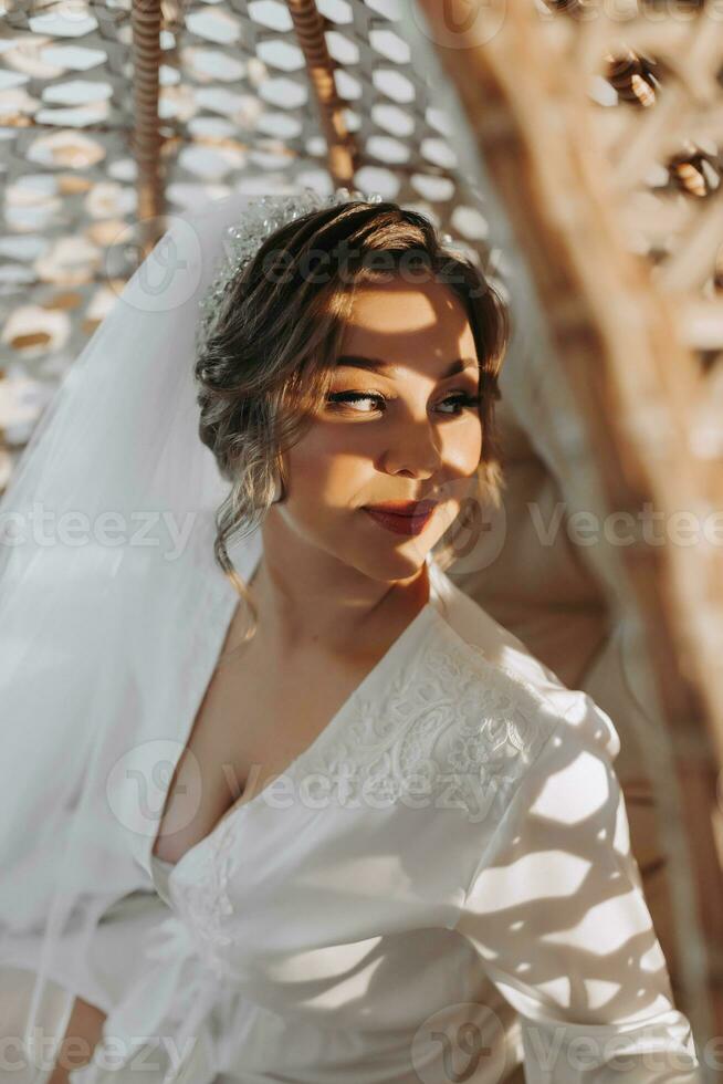 ein schön Braut im ein Kleid mit schön Haar und bilden, Stehen Nächster zu ihr Kleid auf ein Mannequin. Dressing oben und vorbereiten zum das Hochzeit Zeremonie foto