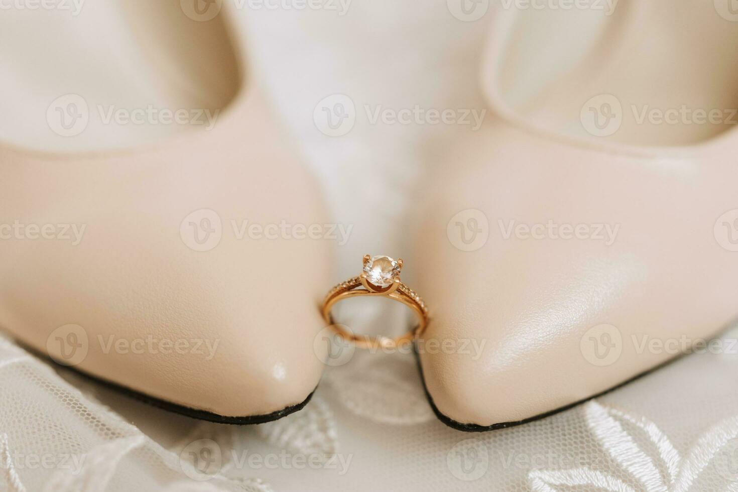 Beige elegant Schuhe. ein Diamant Engagement Ring sitzt zwischen ein Paar von klassisch Hochzeit Schuhe. Mode. Stil. Hochzeit Foto