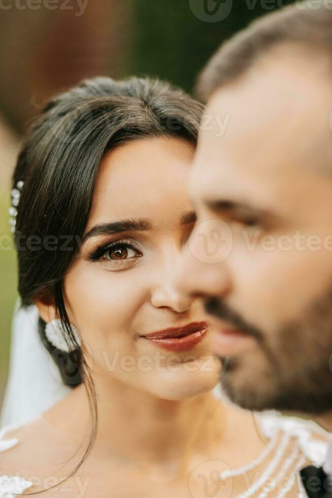 Porträt von ein glücklich frisch verheiratet Ehefrau und Mann umarmen draußen und genießen ein Hochzeit Strauß von Weiß Rosen. aufrichtig Gefühle von zwei jung Personen. das Konzept von wahr Liebe. foto