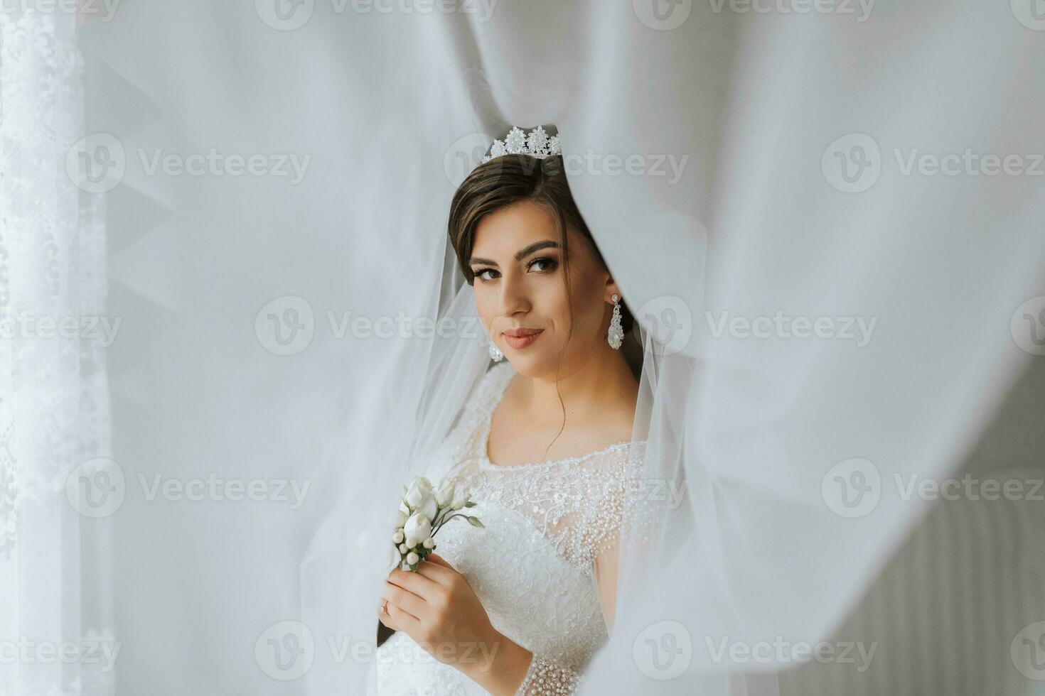 weiblich Schönheit. süß Frau beim heim. das Braut posiert unter ein Schleier. ein stilvoll Frau trägt ein Weiß Kleid. Fachmann bilden und Haar. auf das Braut Kopf ist ein Krone und ein lange Schleier. foto