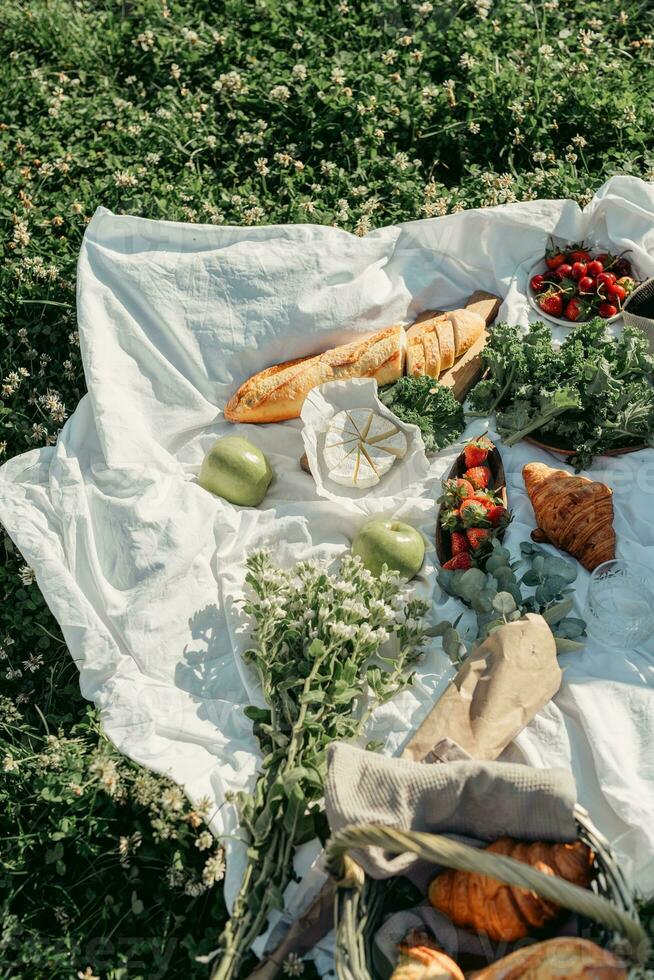 Picknick im das Wiese. Picknick Korb mit Croissants, Früchte und Gemüse. foto