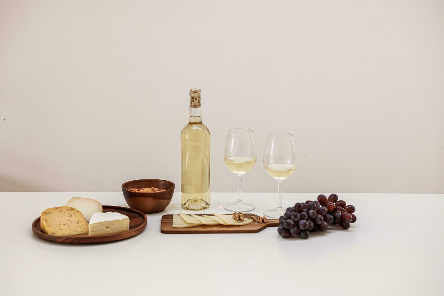 Weiß Wein, Trauben, Käse und Brot auf ein Weiß Tisch. foto