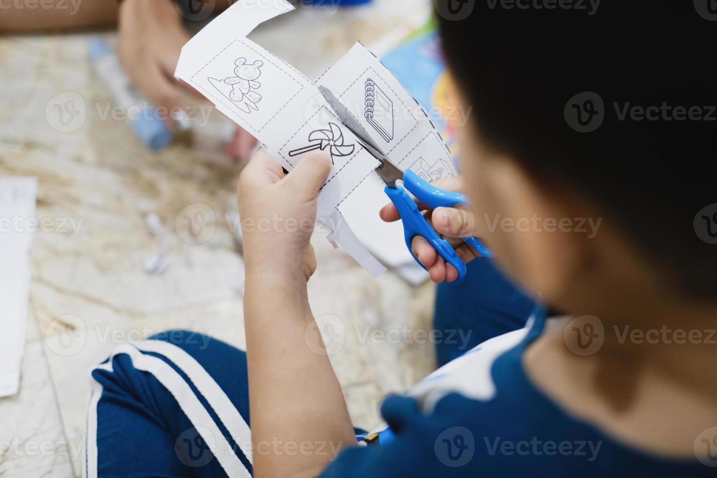 Kinder lernen, mit einer Schere Papier zu schneiden. foto