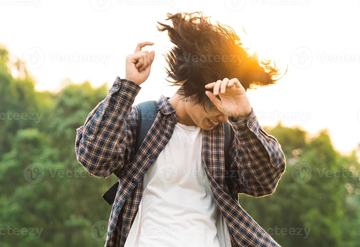 junger asiatischer mann mit langen haaren, der glücklich tanzt foto
