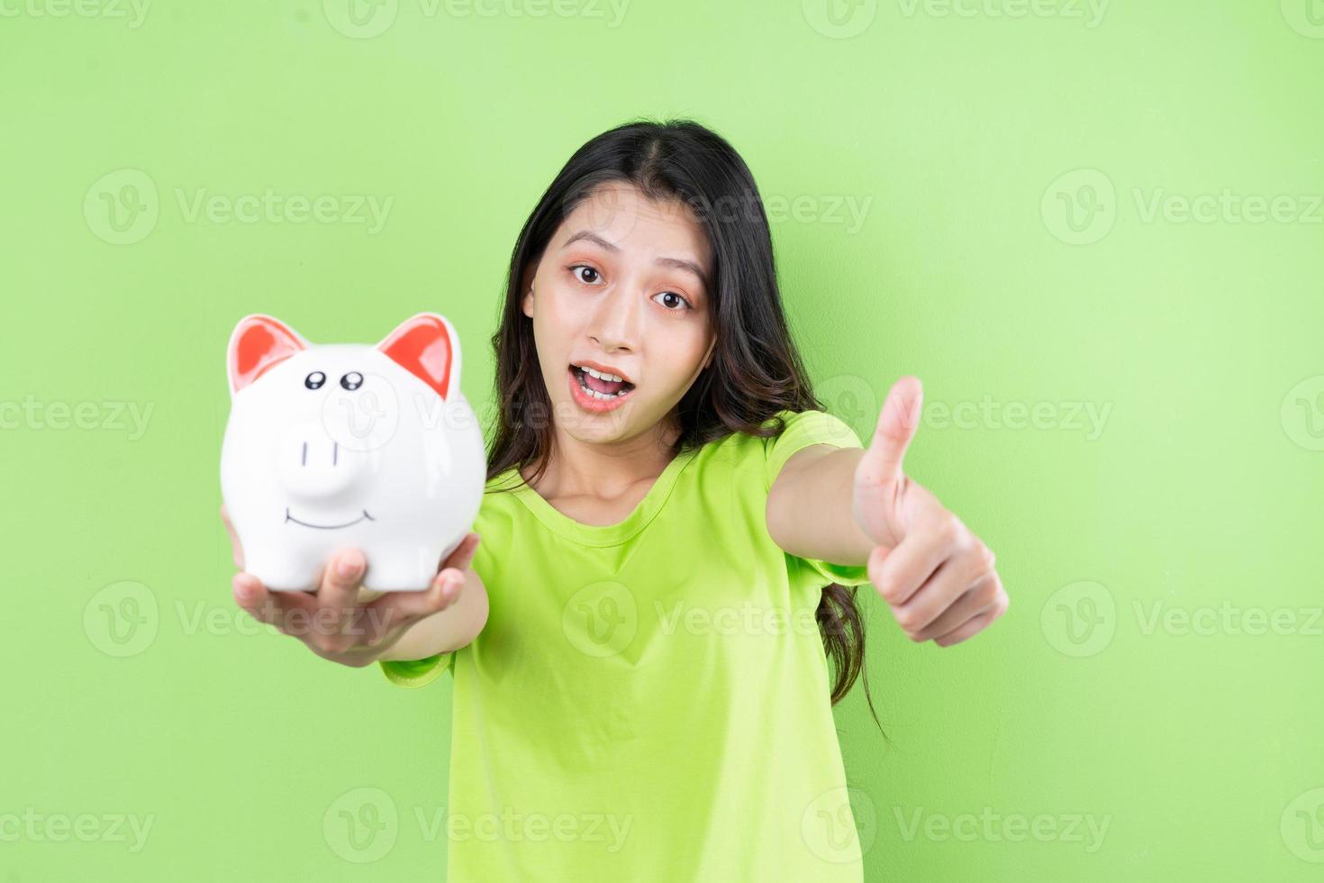 asiatisches mädchen, das sparschwein in der hand hält, geldsparkonzept foto