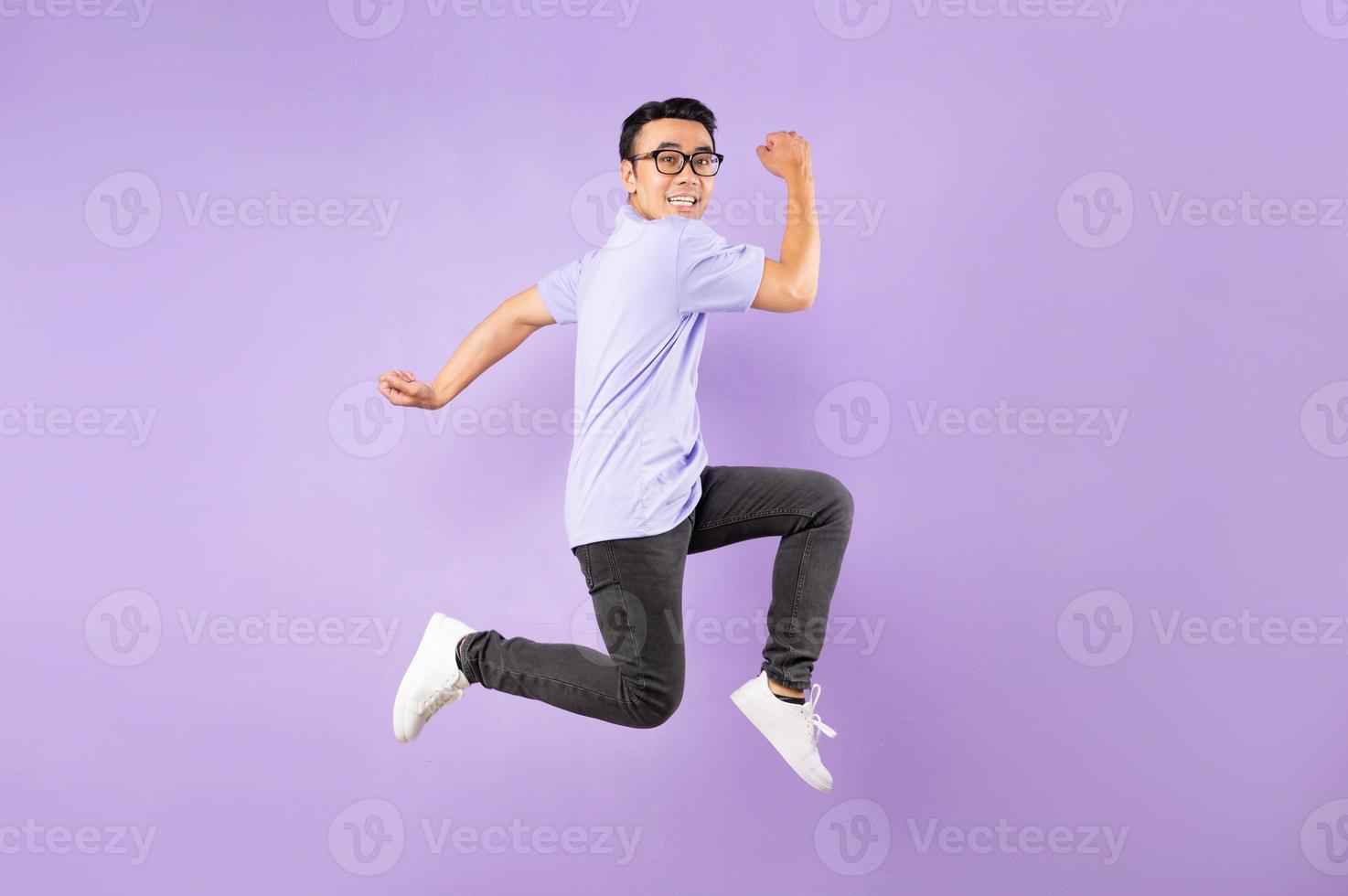 Porträt eines springenden asiatischen Mannes, isoliert auf lila Hintergrund foto