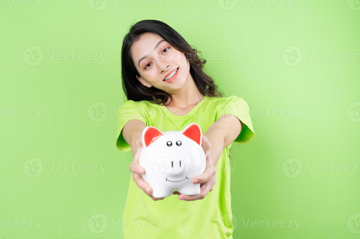 asiatisches mädchen, das sparschwein in der hand hält, geldsparkonzept foto